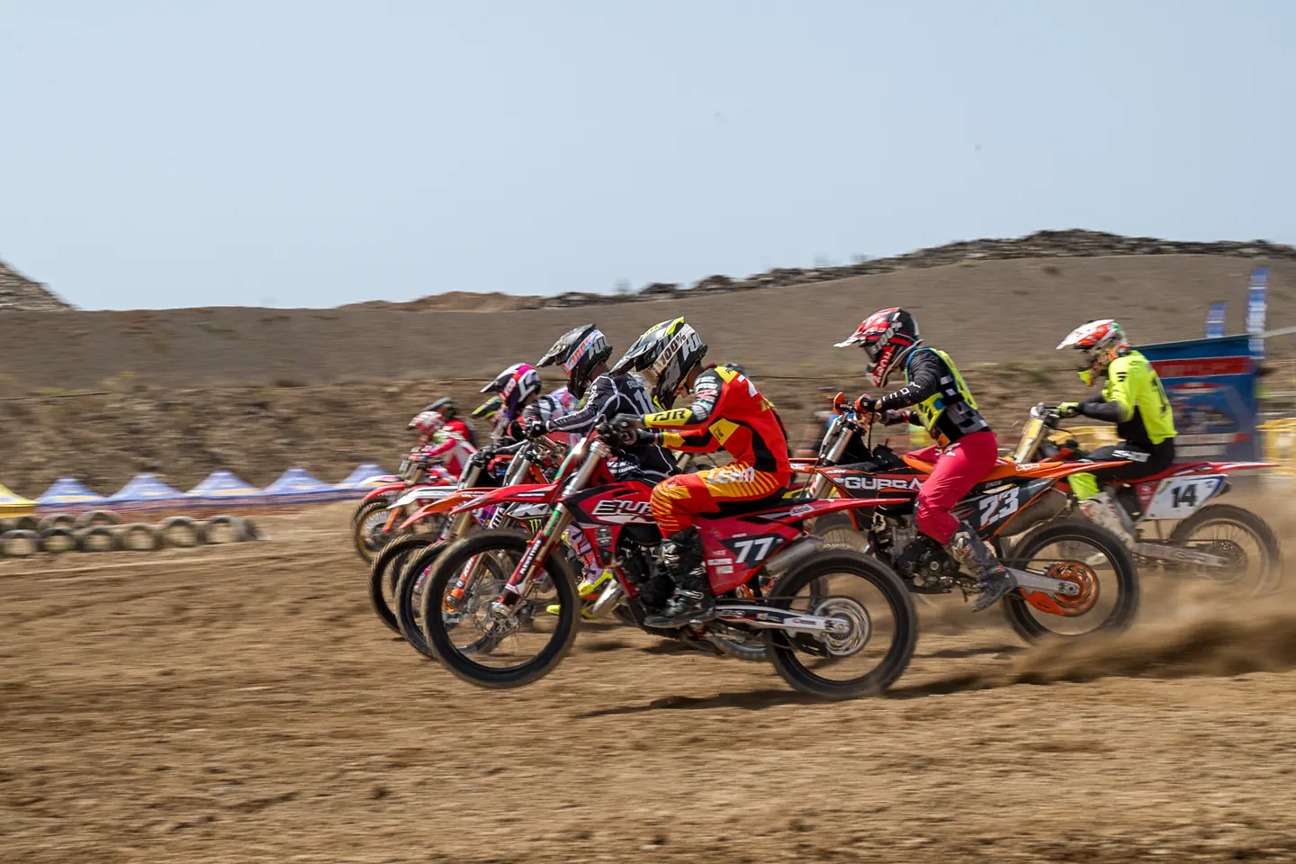 Grupo de pilotos de motocross en plena salida sobre tierra