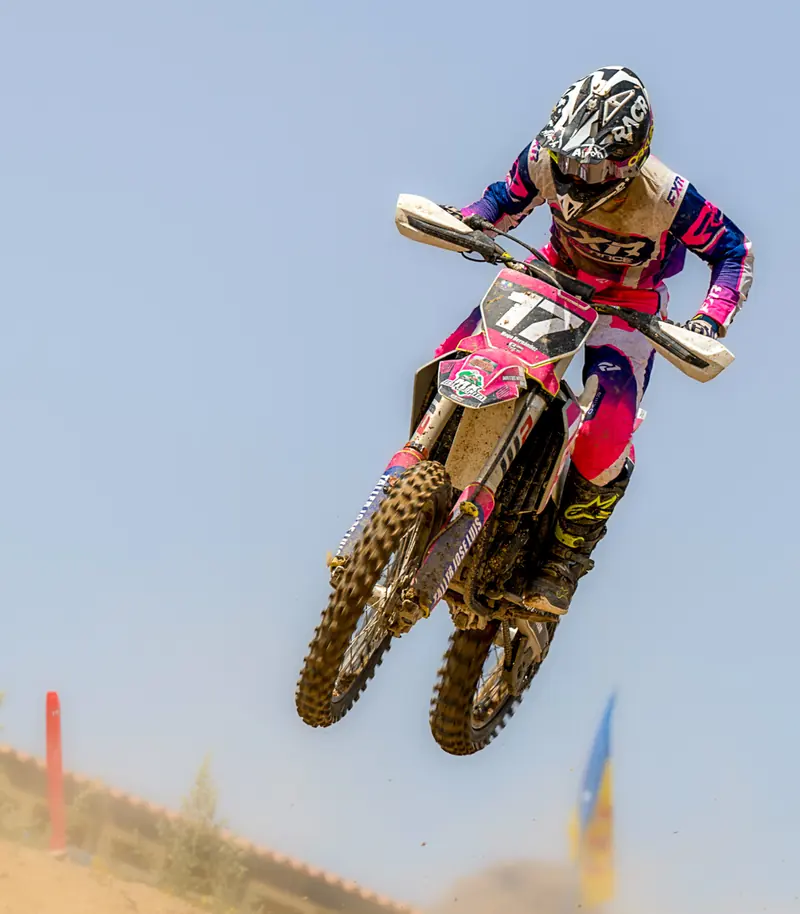 Piloto de motocross en pleno salto contra el cielo