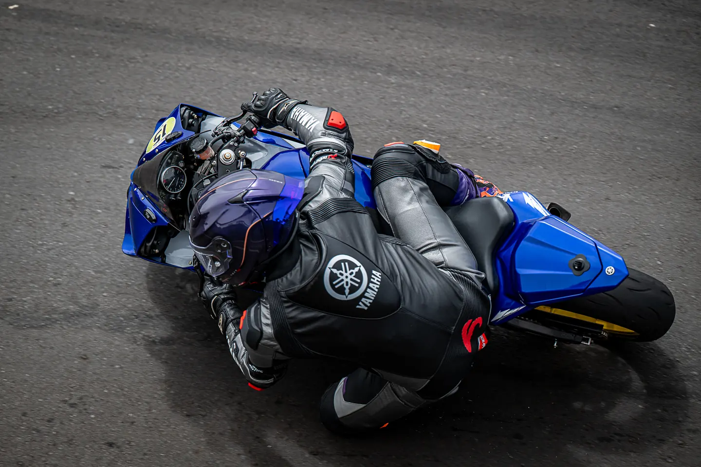 Piloto con moto azul tumbando sobre el asfalto