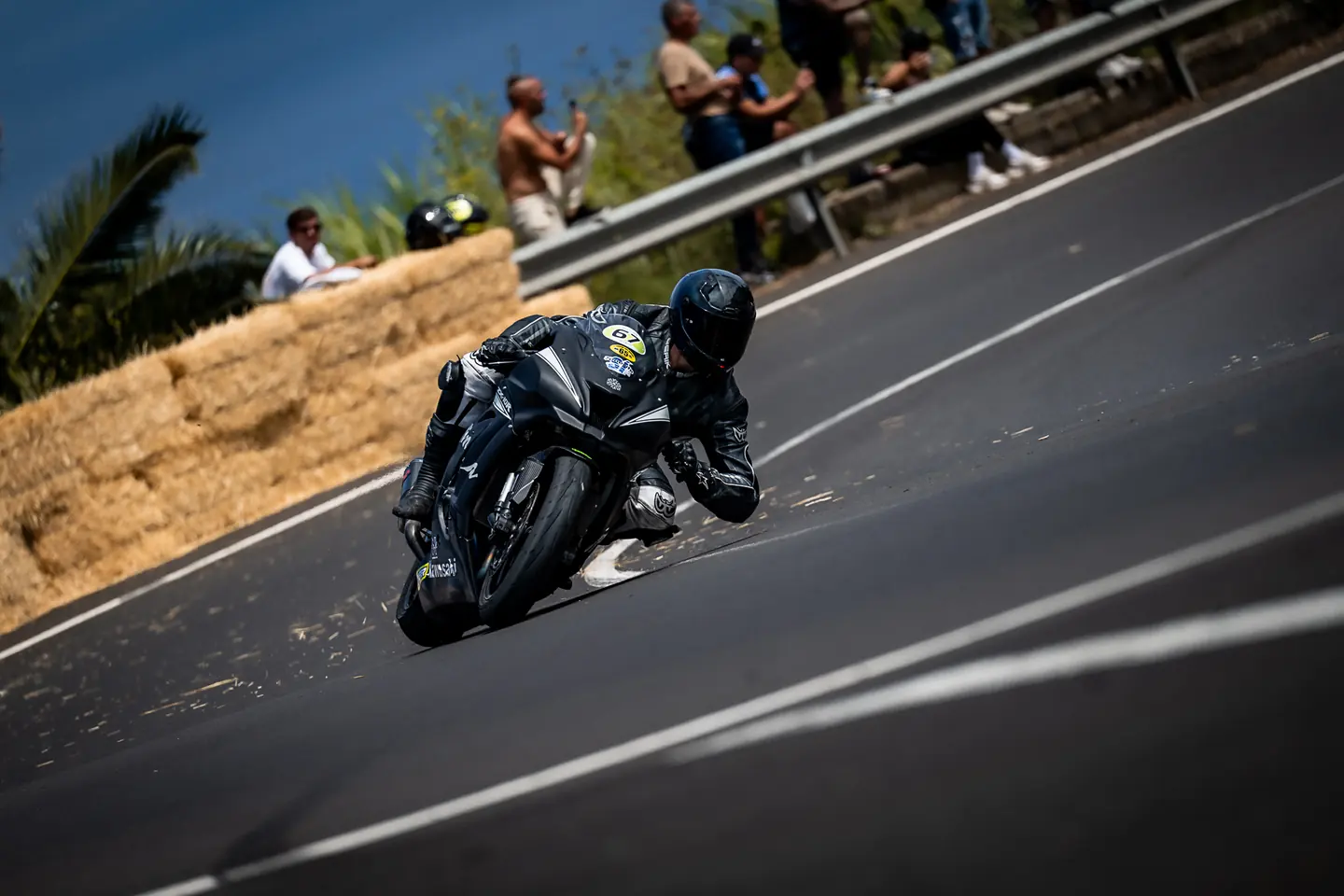Moto negra en una curva con público detrás de las vallas