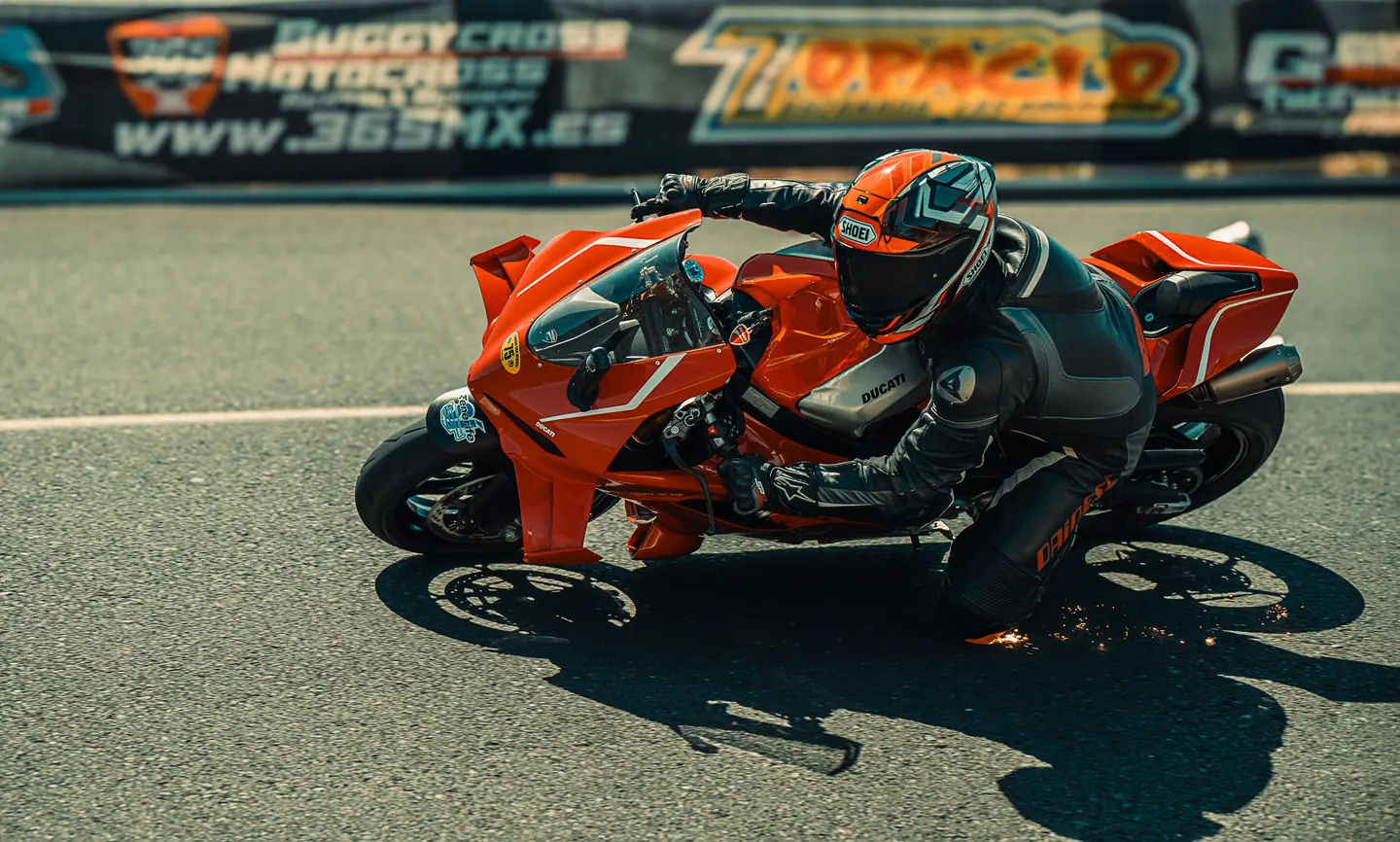 Moto naranja tumbando junto a la publicidad del circuito