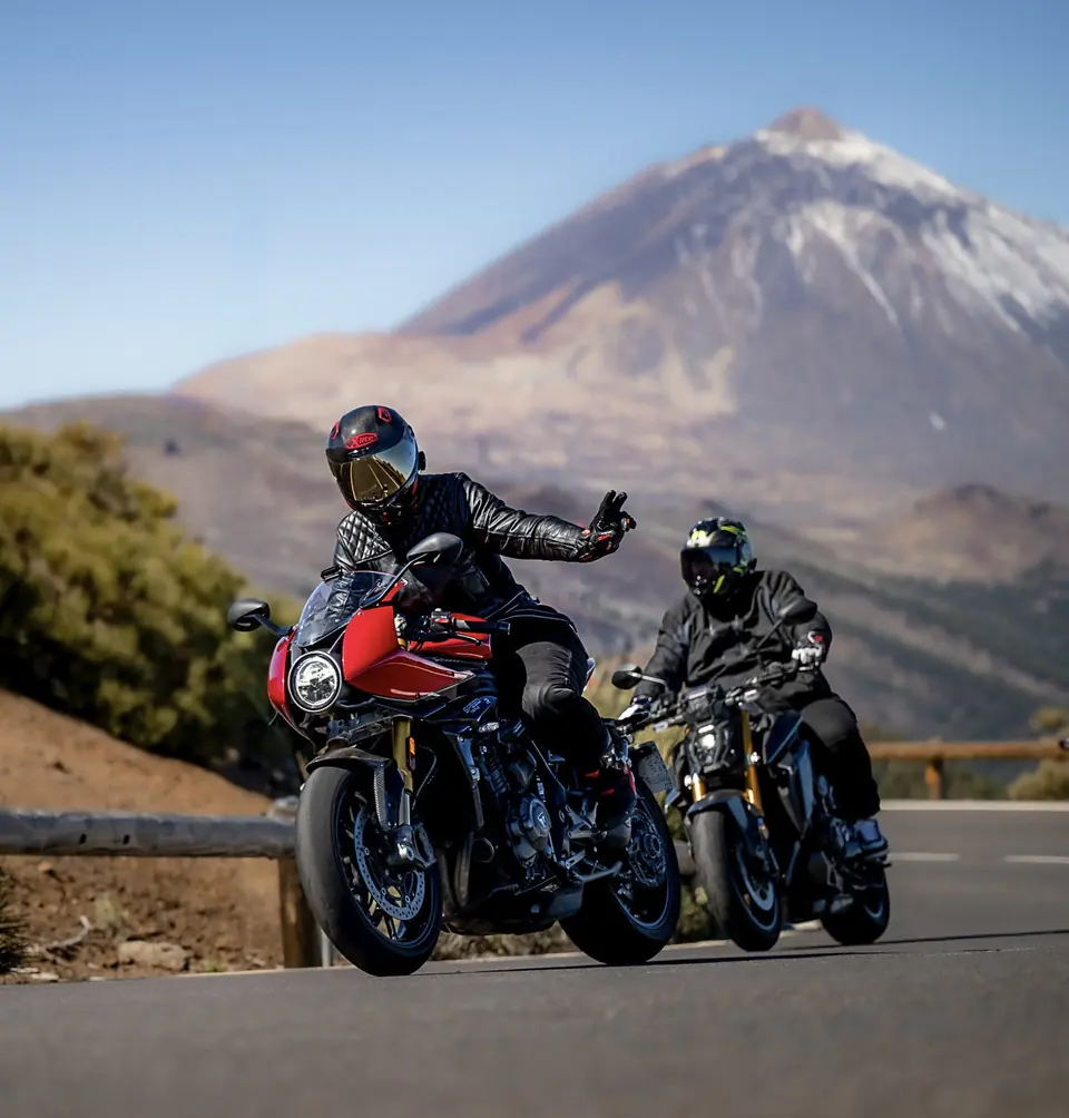 Dos motoristas en ruta con un volcán nevado al fondo
