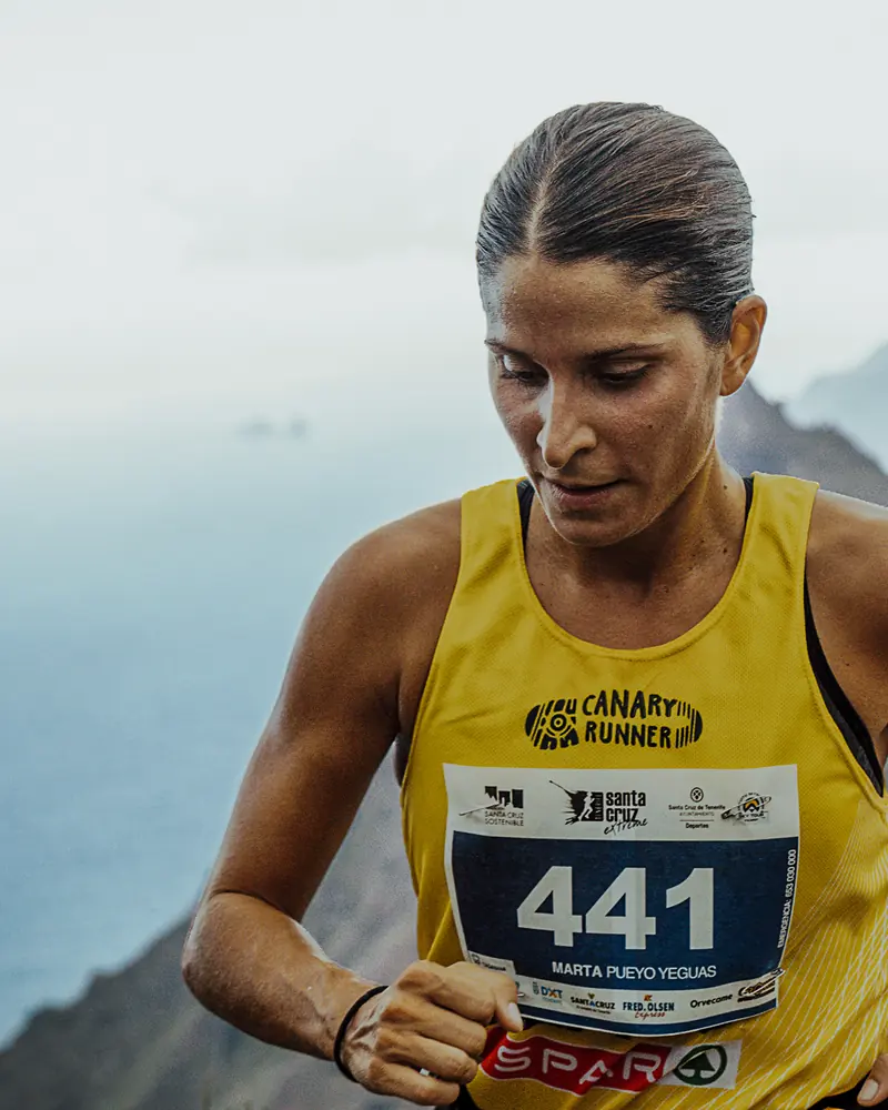 Corredora de trail con dorsal 441 y el mar de fondo