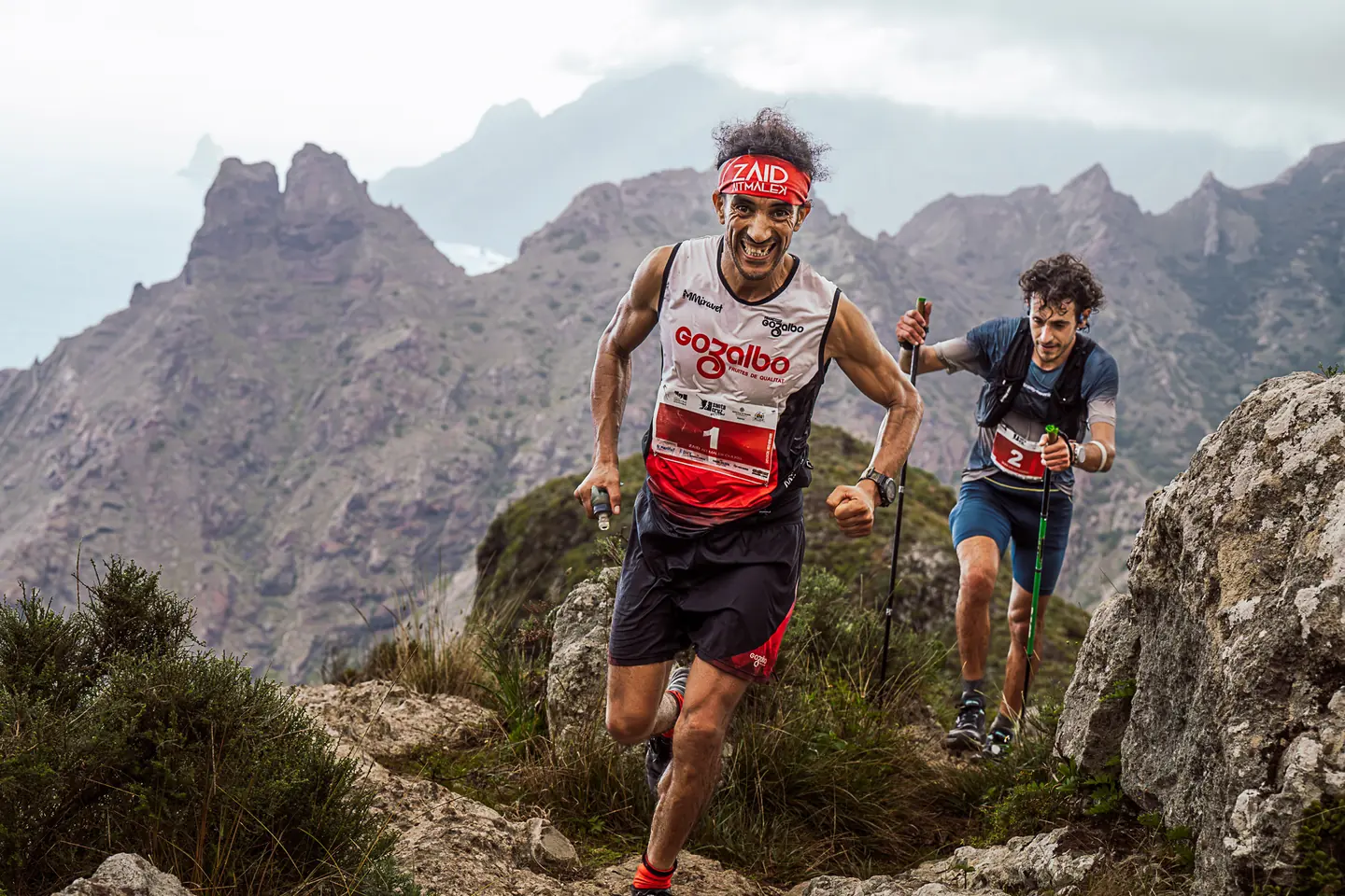 Dos corredores de trail subiendo por un sendero de montaña
