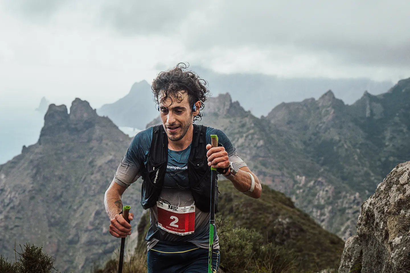 Corredor de trail con dorsal 2 subiendo con bastones